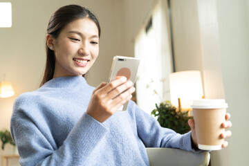 Young Asian woman enjoying a peaceful moment reading a book near window. Calm lifestyle, self-learning, and mindfulness at home.