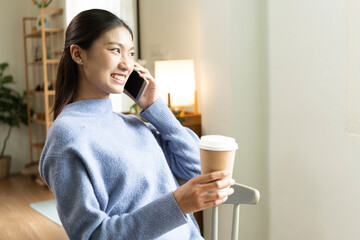 Young Asian woman enjoying a peaceful moment reading a book near window. Calm lifestyle, self-learning, and mindfulness at home.