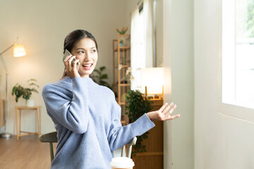 Young Asian woman enjoying a peaceful moment reading a book near window. Calm lifestyle, self-learning, and mindfulness at home.