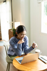 Young Asian woman enjoying a peaceful moment reading a book near window. Calm lifestyle, self-learning, and mindfulness at home.