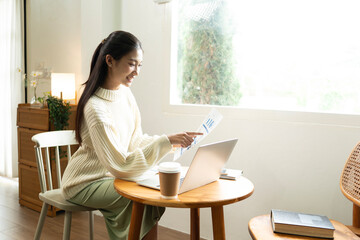 Young Asian woman enjoying a peaceful moment reading a book near window. Calm lifestyle, self-learning, and mindfulness at home.