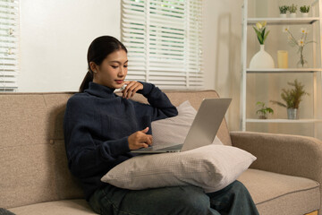 Young Asian woman enjoying a peaceful moment reading a book near window. Calm lifestyle, self-learning, and mindfulness at home.