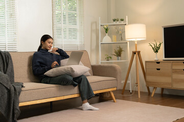 Young Asian woman enjoying a peaceful moment reading a book near window. Calm lifestyle, self-learning, and mindfulness at home.