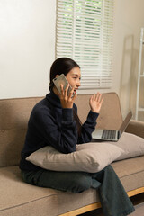 Young Asian woman enjoying a peaceful moment reading a book near window. Calm lifestyle, self-learning, and mindfulness at home.