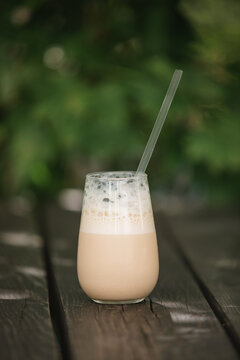 Close-up of an Iced coffee latte with frothy foam on a wooden garden table