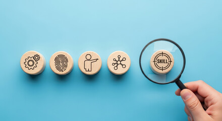 Skill Development Concept Featuring Wooden Blocks with Icons and a Magnifying Glass Focusing on Skill Acquisition and Professional Growth on Blue