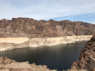 Landscape view of Hoover Dam and Lake Mead surrounded by desert mountains in Nevada, USA, under a clear sky.
