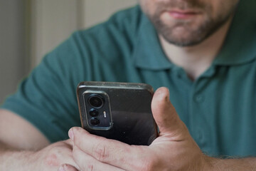 Man using his cellphone. Handsome guy use mobile phone at home. Male browses social networks, gaming, does shopping online, chats with friends, writes or reads messages. Close up. 4k video footage