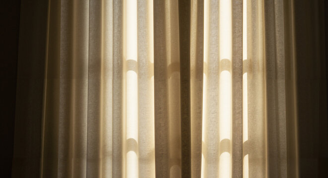 Sheer curtains illuminated by sunlight in a soft, warm tone  