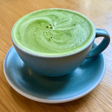 Close-up of a matcha latte in a teacup on a wooden table