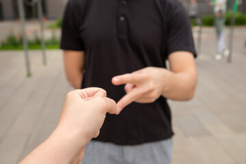 Two people engaging in a hand game rock paper scissors outdoors in a city setting during the day