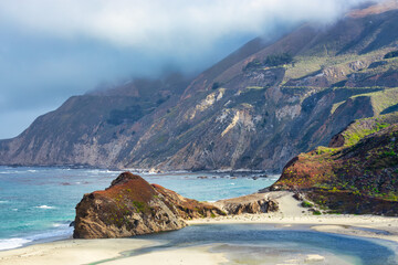 Scenic Highway 1 in Big Sur, California USA, with winding road, green coastal mountains, and low clouds rolling over ridges, a breathtaking Pacific Coast travel destination