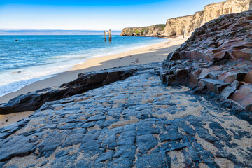 Ruins of the old pier with graffiti and swing at Davenport Pier Beach, California, USA. Iconic coastal landmark near Santa Cruz, where sandy shores meet the Pacific Ocean under blue skies