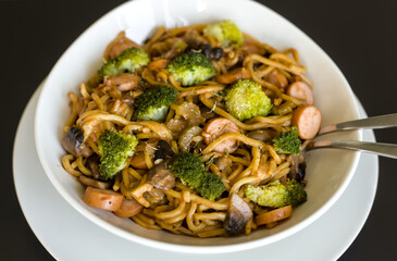 Close Up of Stir Fry Egg Noodles with Bockwurst Sausages, Mushrooms, Onions, Broccoli, White Bowl