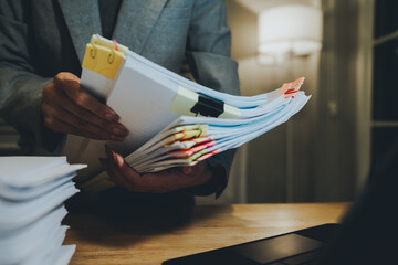 A person organizing a large stack of documents with binder clips on an office desk, representing...