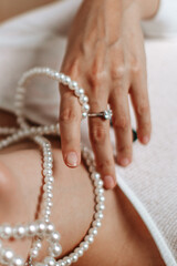 Fashion accessories details of woman's hand with diamond engagement ring and white pearl beads