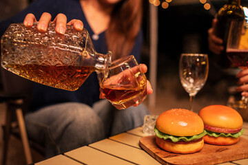 Women sit pouring whiskey into glasses to celebrate.
