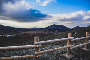 Fototapeta premium Scenic View of Mountain Landscape with Sun Rays and Wooden Fence at Sunset