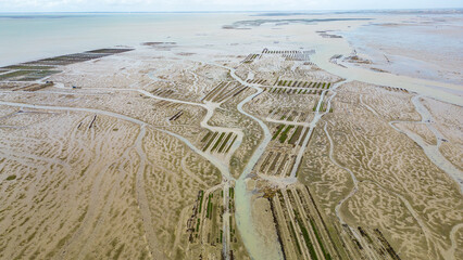 Aerial view of oyster farms at low tide near the Passage du Gois, Noirmoutier Island, France. Long rows of oyster beds and water channels create a unique landscape, showcasing traditional oyster
