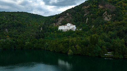 Aerial view of abbey of San Michele surrounded by trees. It is a Benedictine Abbey located at the foot of Monte Vulture, on the flank of the Monticchio Lake Piccolo, in Basilicata, Italy.