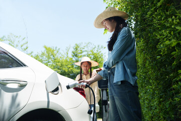 Farmer woman is holding a battery charger to charge her EV.