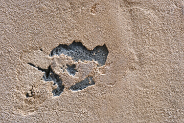Wall texture showing peeling plaster and exposed surface in a close-up view at an outdoor location