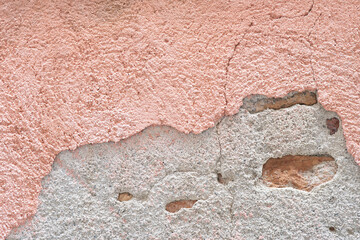 Textured wall featuring pink plaster and rough stone surfaces in a rustic setting