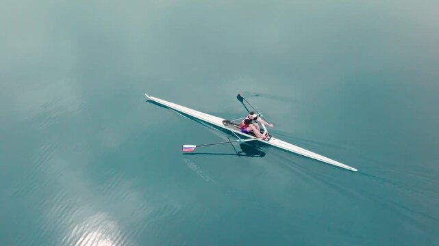 Rowing Top view of professional rower in racing boat, symbol of strength, determination and healthy active lifestyle. Single scull athlete training on water, in slow motion video 120fps.