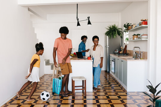 Siblings playing with a soccer ball in a Brazilian kitchen, enjoying family time - Powered by Adobe