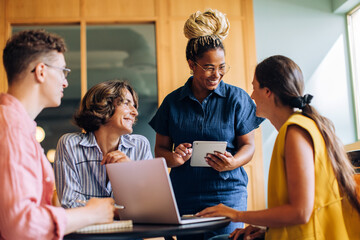 Business team discussing ideas using a tablet and laptop at the office