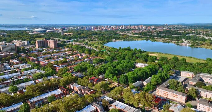 Rising over the green neighborhood of New York with a big pond. Numerous cars rush by the highway.