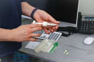 Close-up of audiologist hand preparing ear impression syringe for custom molded hearing aid or ear plug in clinic.