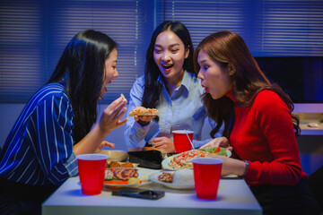 Asian businesswomen coworkers eating takeaway pizza and food, enjoying friendship at office late night working overtime