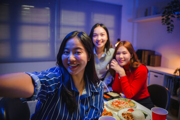 Young Asian women friends smiling and taking a selfie at a dinner party celebrating friendship and happiness together at home