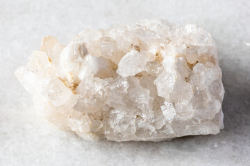 rough druse of clear quartz rock on white marble