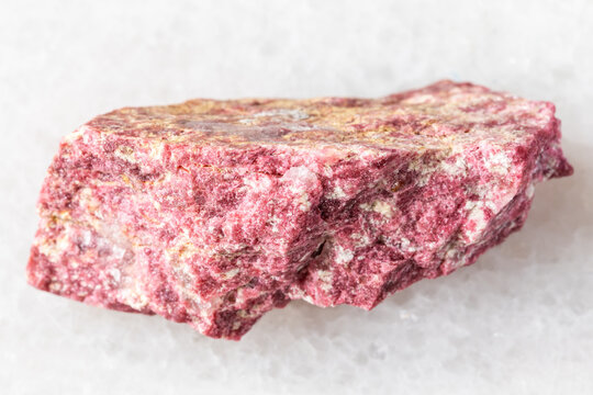 sample of raw thulite rock on white marble