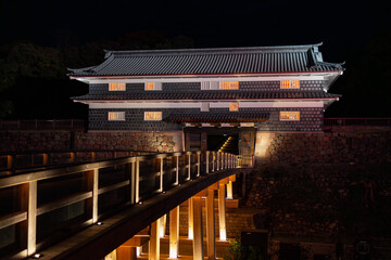 Naklejka premium Entrance to Kanazawa Castle at night with illuminated bridge and traditional gate structure highlighted by warm architectural lighting