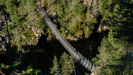 A breathtaking view of the Canyon Lake Julma Olkky in Hossa National Park, Finland, showcasing a wooden bridge crossing a serene body of water surrounded by lush greenery.