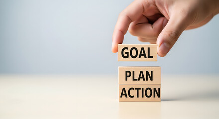 Hand stacking wooden blocks spelling goal plan action for success and achievement