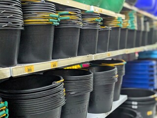 Close-up view of various black plastic buckets stacked neatly on shelves in a store.