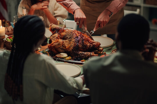 Family celebrating thanksgiving, carving roasted turkey at home dinner table