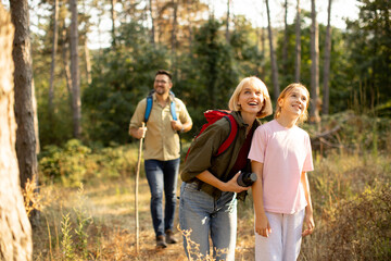 Fototapeta premium Family enjoys nature hike in the forest during sunny afternoon with smiles and laughter