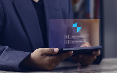 Businessman using a futuristic tablet with a holographic login screen for secure authentication. The shield icon represents robust cybersecurity, data protection, and privacy in the digital network.
