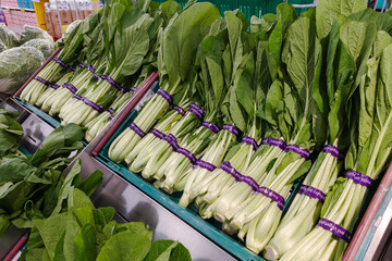 Fresh bunches of Choy Sum (Chinese green) vegetables neatly arranged on display at a supermarket...