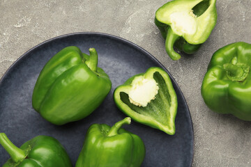 Green sweet pepper bell on dark plate on grey background.