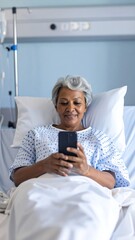 Senior woman using phone in hospital bed