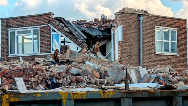 Brick building demolition with collapsed roof and debris, useful for construction, insurance, and disaster-related topics