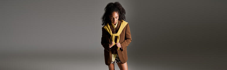 Fototapeta premium Stylish autumn outfit showcased by a confident black woman in a studio setting