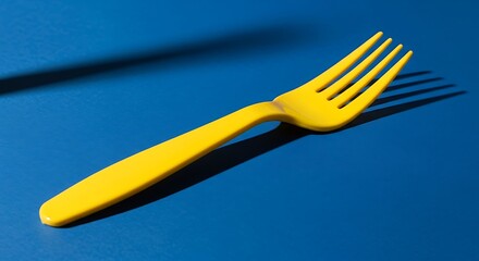 Bright Yellow Fork Casting a Shadow on a Vibrant Blue Surface