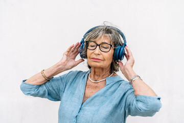 Senior woman enjoying music with closed eyes and headphones